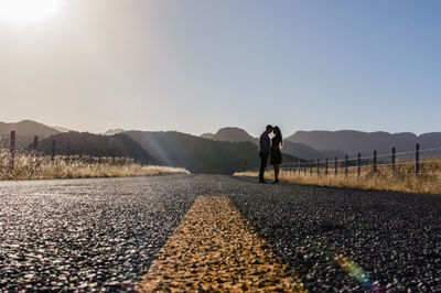 Couple standing on road against clear sky