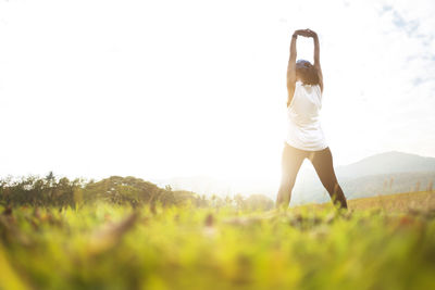 Rear view of woman with arms raised against sky