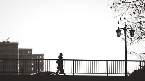 People standing on railing against clear sky