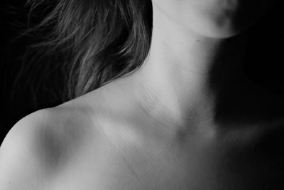 Close-up of shirtless woman against black background