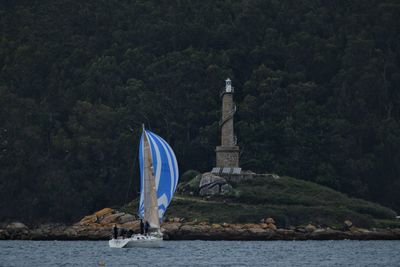 Sailboat in sea against mountain