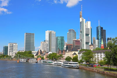 Modern buildings by river against sky in city