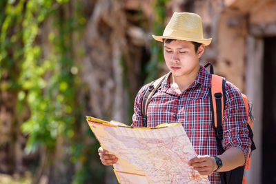 Backpacker reading map while standing against old historical building