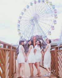 Full length of friends wearing white dress while enjoying in amusement park