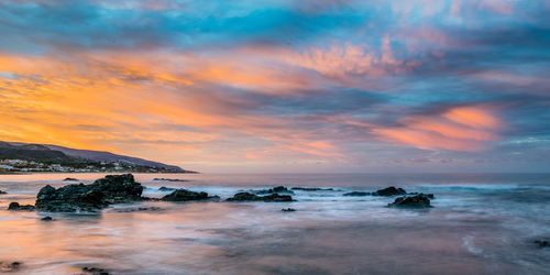 Scenic view of sea against cloudy sky during sunset