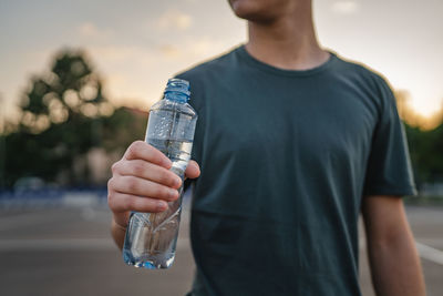 Midsection of man drinking water bottle