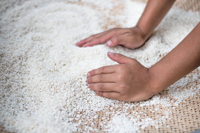 Cropped image of woman collecting rice in wicker container