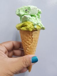 Cropped hand of woman holding ice cream on white background