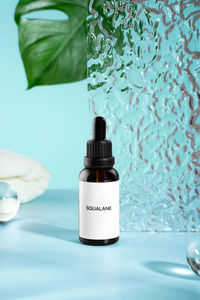 Anti aging squalane. serum with collagen and peptides on blue surface with shadows. hyaluronic acid