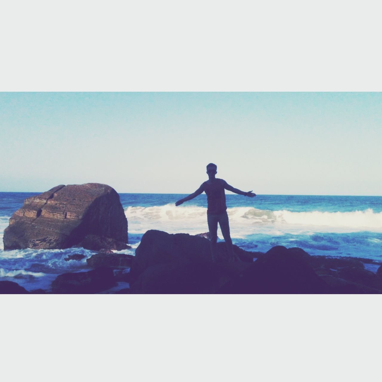 sea, horizon over water, water, clear sky, lifestyles, leisure activity, rock - object, beach, copy space, standing, shore, scenics, rear view, men, beauty in nature, tranquil scene, tranquility, rock formation