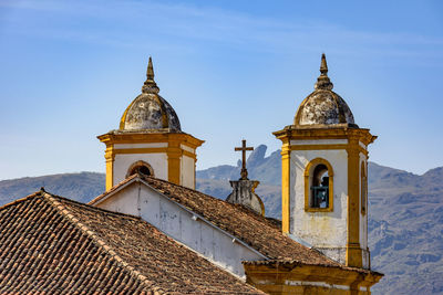 Bell towers of baroque church in the city of ouro preto during sunset with the mountains