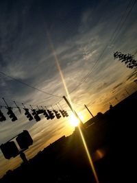 Low angle view of silhouette cables against sky during sunset