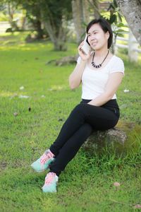 Beautiful young woman using mobile phone in field