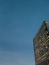 Low angle view of illuminated buildings against clear blue sky