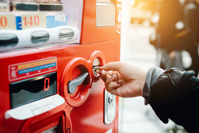 Close-up of woman inserting coin in vendor machine