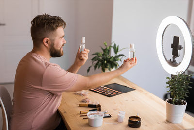 Side view of man using mobile phone while sitting at home