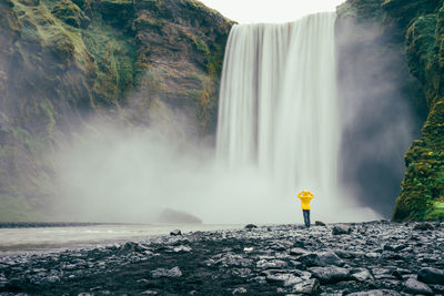 Bright hiker at the base of the powerful waterfall in iceland