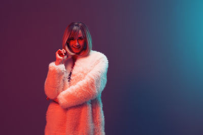 Portrait of young woman wearing sunglasses against black background