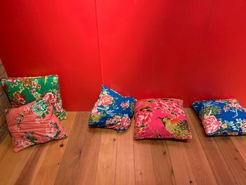 Multi colored cushions on hardwood floor against red wall