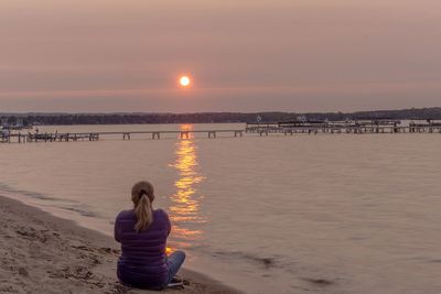 Rear view of women standing at beach during sunset