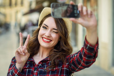 Portrait of smiling young woman taking selfie through mobile phone