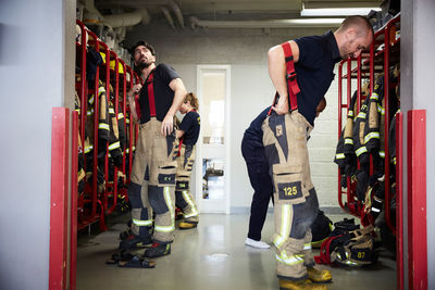 Firefighters wearing protective workwear in locker room at fire station