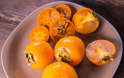 Persimmon cut into halves on a plate on a wooden table,copy space,closeup