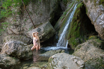 Woman standing by waterfall in forest