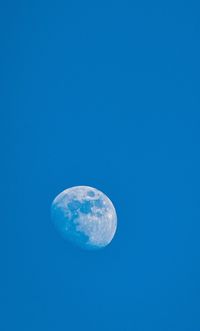 Low angle view of moon against clear blue sky