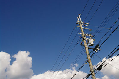 Low angle view of electricity pylon against blue sky