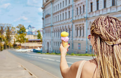 Ice cream cone in hand close-up with bokeh. gelato with peach sorbet and lavender flavor. 