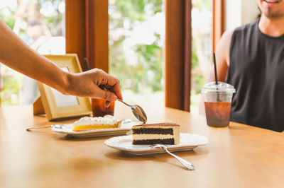 Woman's hand holding spoon eating cake in cafe.