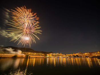 Firework display over river against sky at night