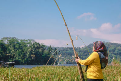 Woman standing on field against sky