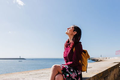 Young woman looking away in sea against sky