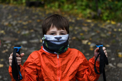 Portrait of boy wearing raincoat while standing in forest