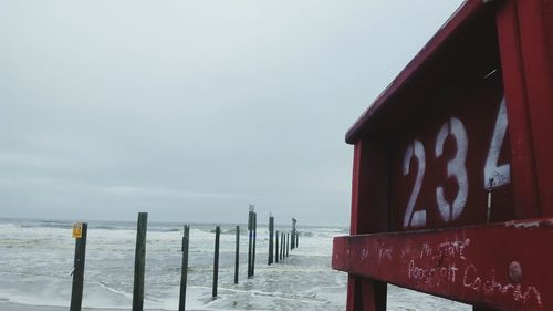 Wooden posts on beach against sky