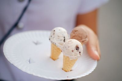 Midsection of woman holding ice creams in tray outdoors