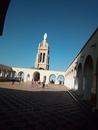 Group of people outside temple against clear blue sky