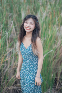 Portrait of young woman standing against plants