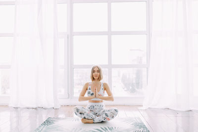 Girl in a sports uniform does exercises, physical exercises, yoga and stretches on a rug against