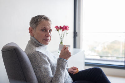 Portrait of smiling woman sitting by window