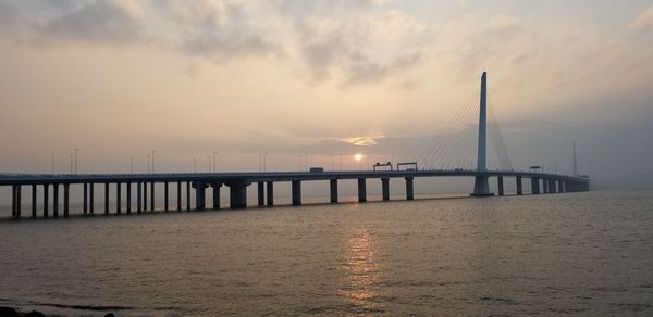 Bridge over river against cloudy sky