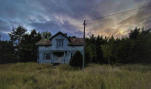 Houses and trees on field against sky at sunset