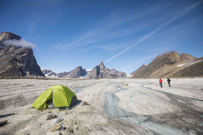 People on rocks against mountains