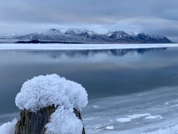 Frozen lake by snowcapped mountain against sky