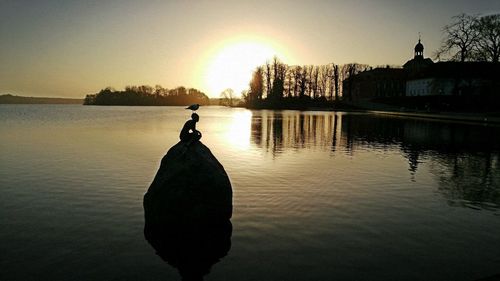 Silhouette man with umbrella against sky during sunset