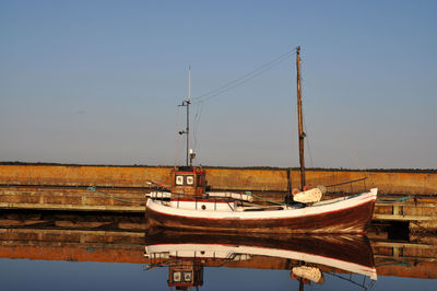 Ship moored on shore against clear sky