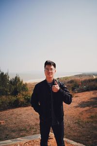 Portrait of young man standing on land against sky