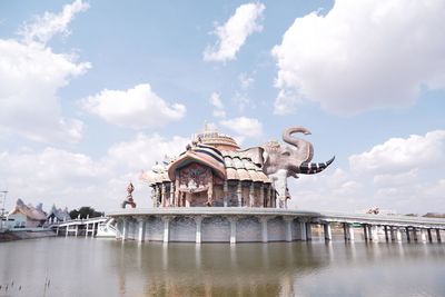 Statue of bridge over water against cloudy sky